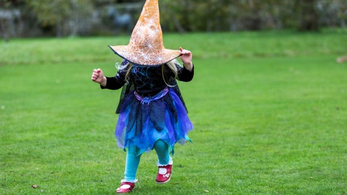 Young child in a witch's costume with the hat over her head